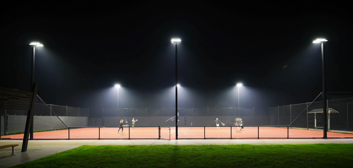 4 people playing tennis under lights